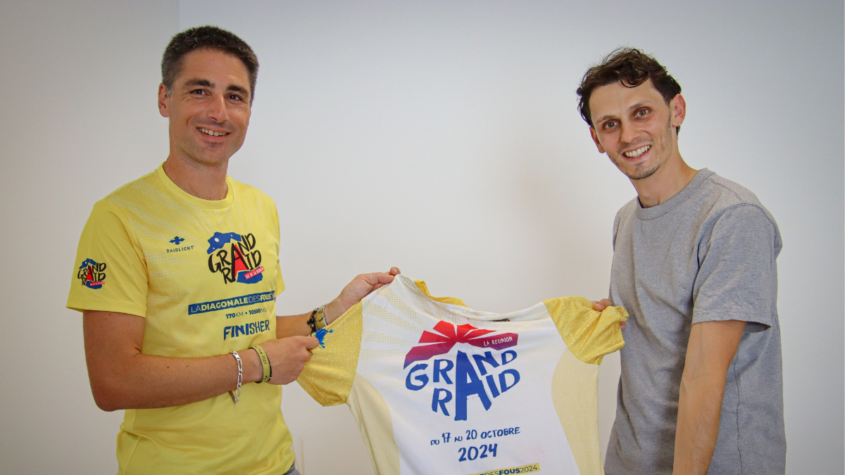 Léo-Paul avec deux joueurs du FCBJ devant le mur média du club avec les logos sponsors