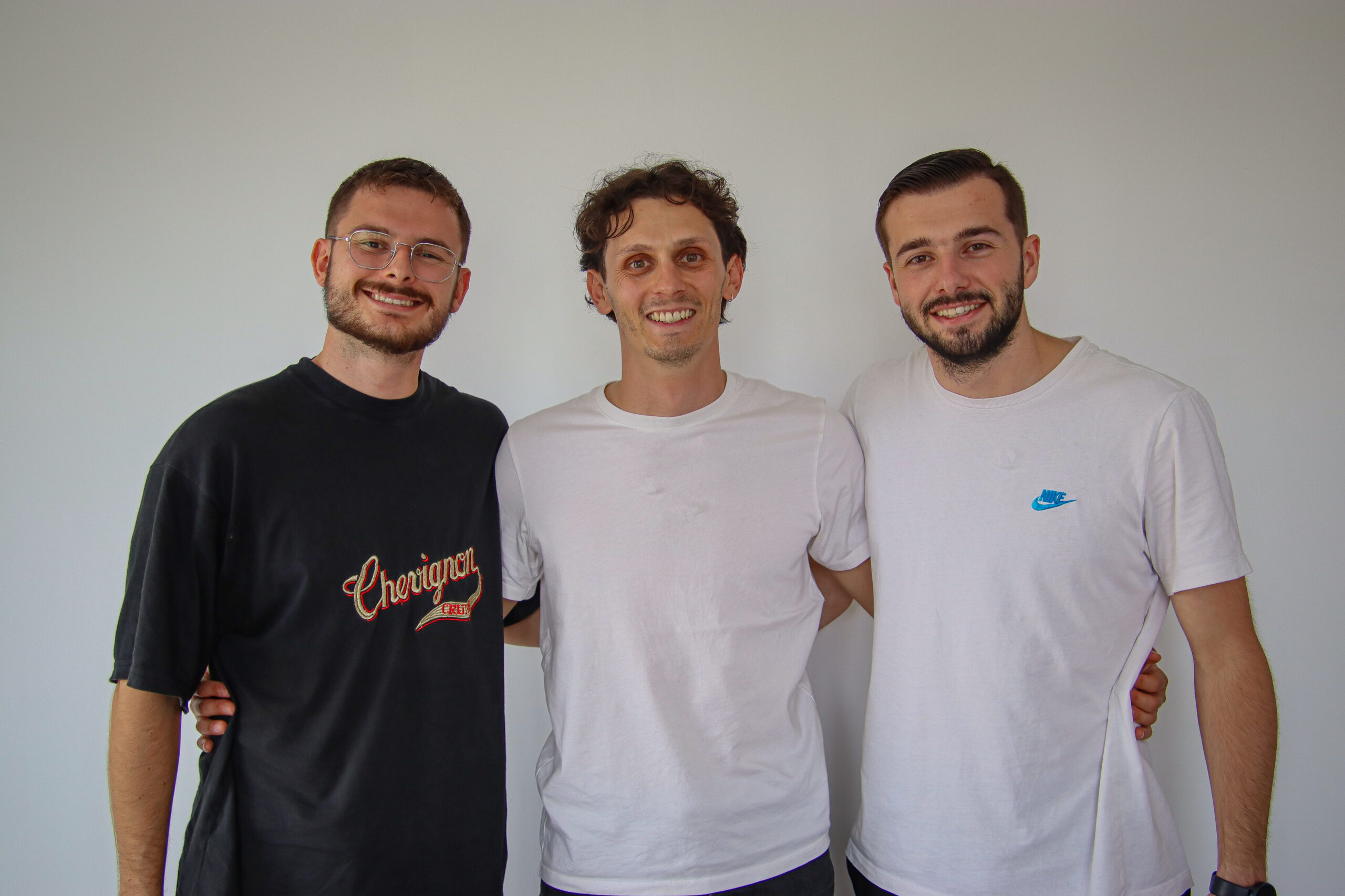 Léo-Paul avec deux joueurs du FCBJ devant le mur média du club avec les logos sponsors